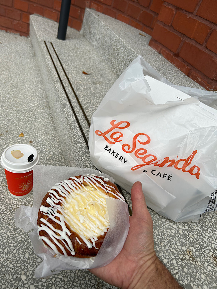 A cheese danish and a coffee beside a La Segunda Bakery bag, on the steps of El Reloj